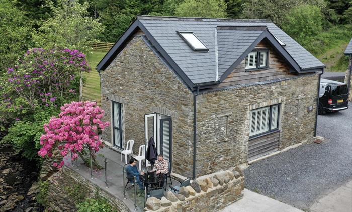 Traditional stone holiday cottage with riverside patio and rhododendron blooming
